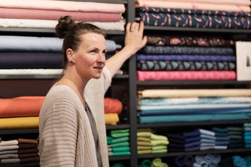 Eine Frau zeigt auf Stoffe in einem Regal