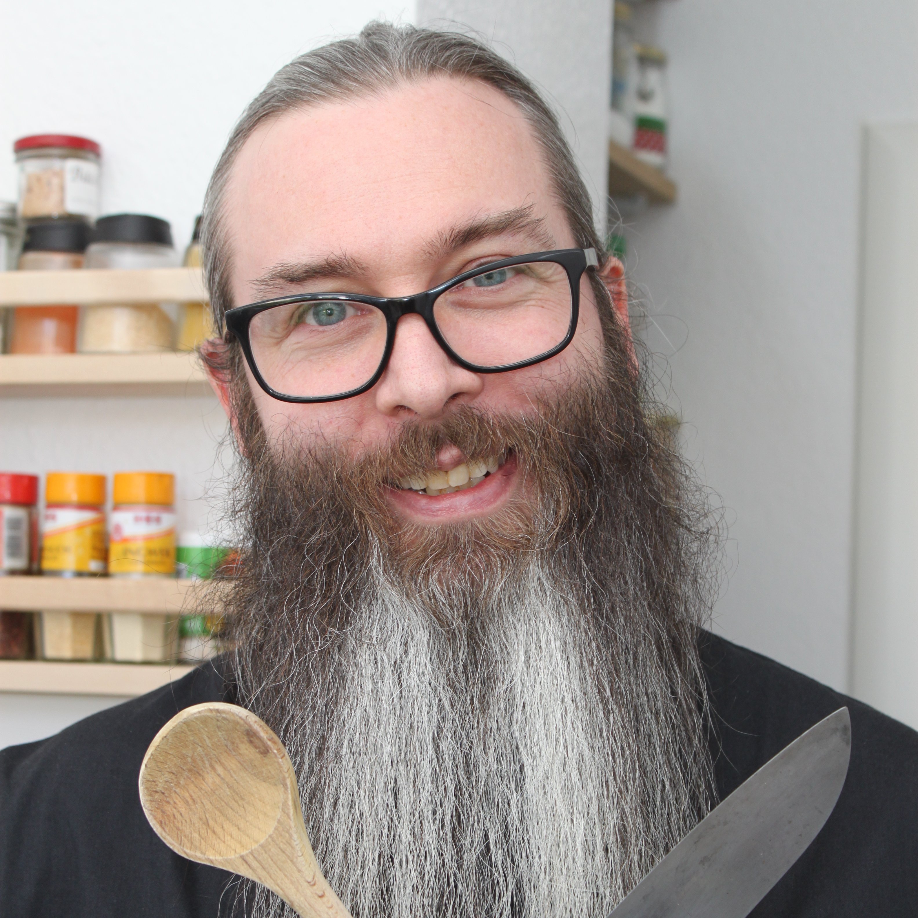 Paul Schad hält einen Kochlöffel und ein Messer über Kreuz