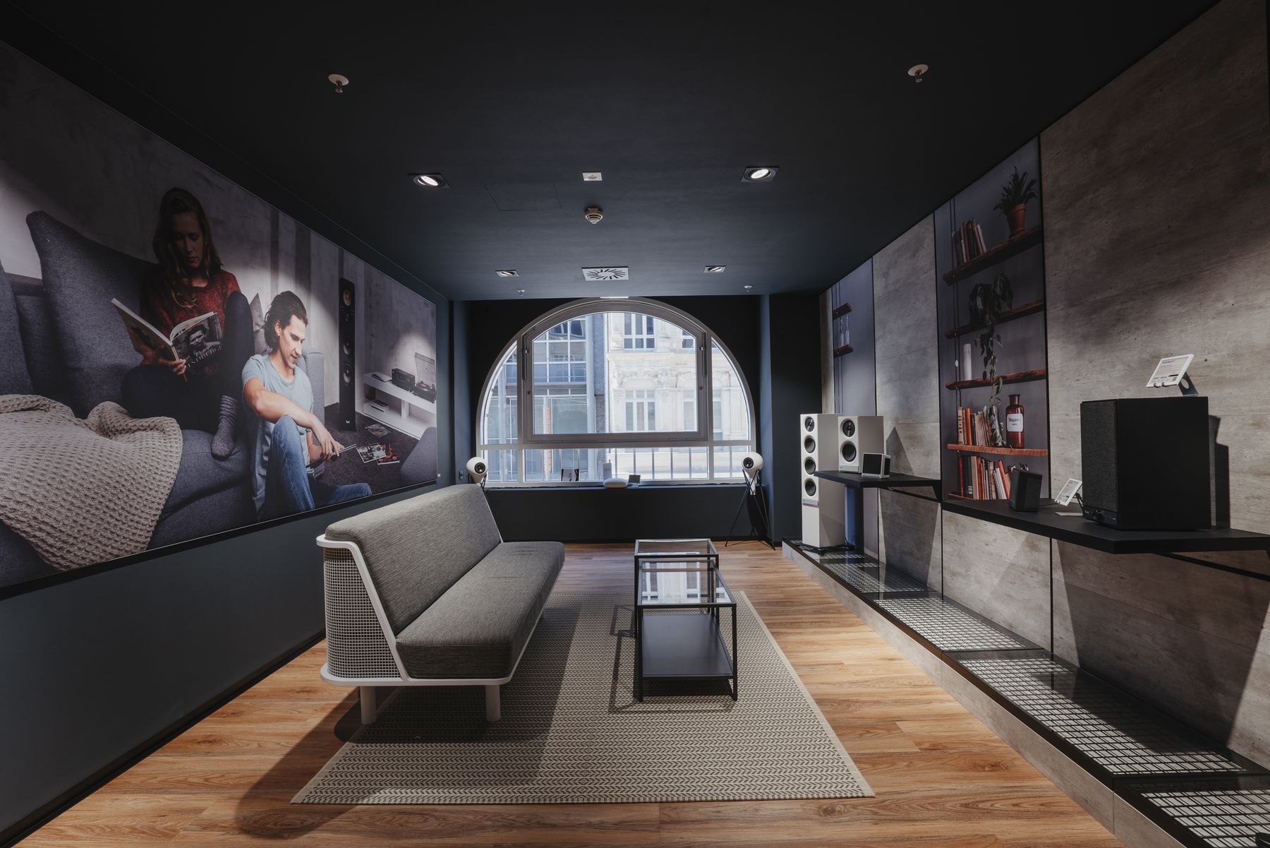 Blick in einen großen Raum mit Fenster. Ein Sofa und Lautsprecherboxen.